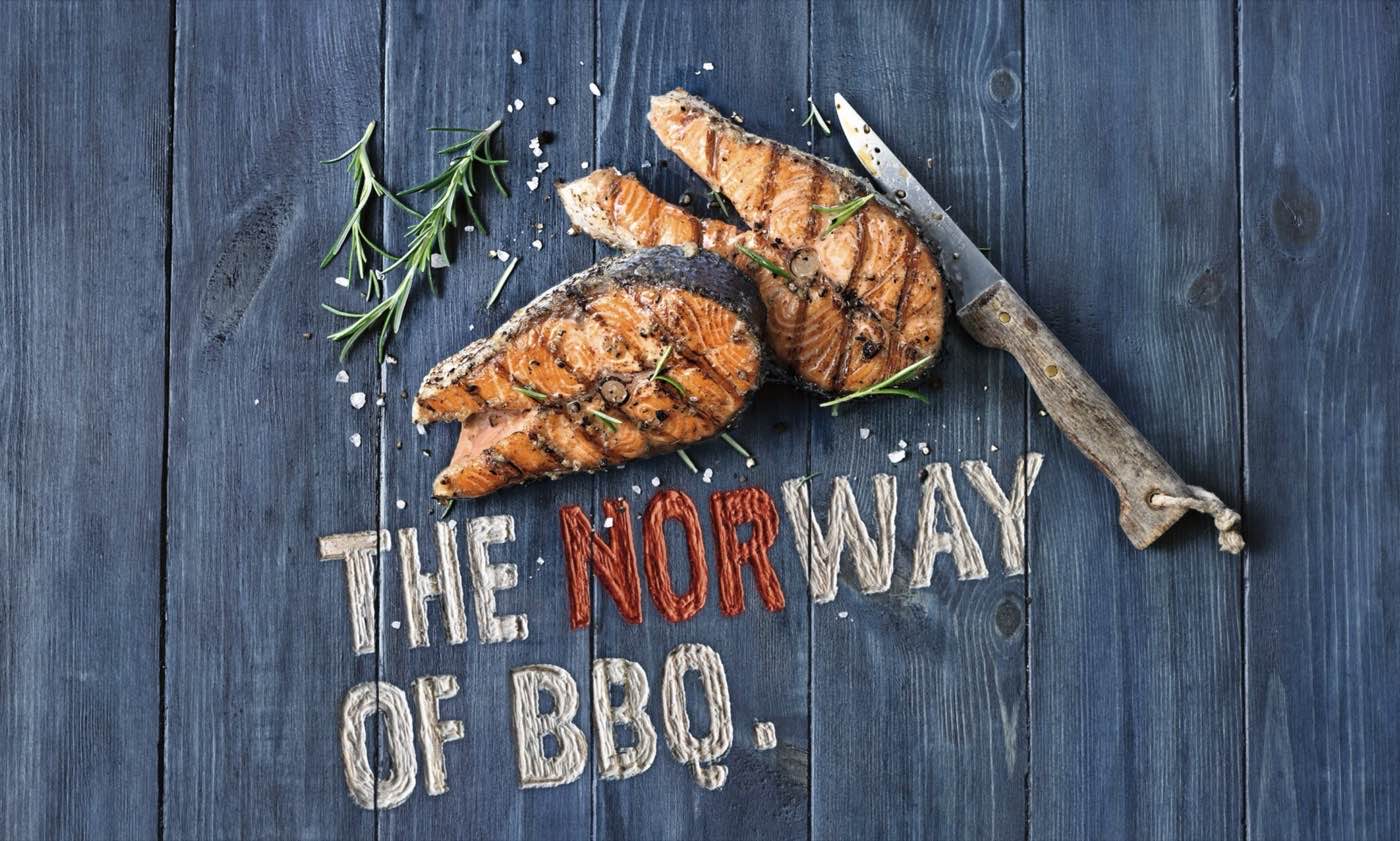 Gegrillte Lachskoteletts auf dunklem Holz, Schriftzug „The Norway of BBQ“